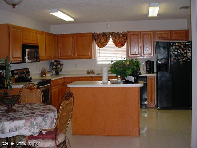 2498 Mallory Hills Road Jacksonville, FL 32221 - Photo 3 of 9 a kitchen with stainless steel appliances granite countertop a refrigerator a stove a sink a dining table and chairs with wooden floor
