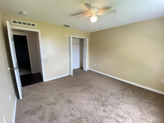an empty room with windows and chandelier fan