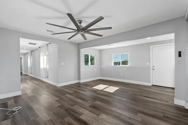 a view of an empty room with wooden floor and a window