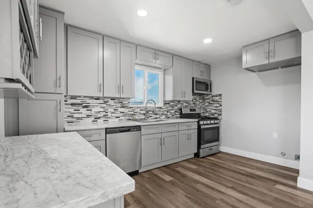 a kitchen with stainless steel appliances kitchen island granite countertop a sink stove and refrigerator