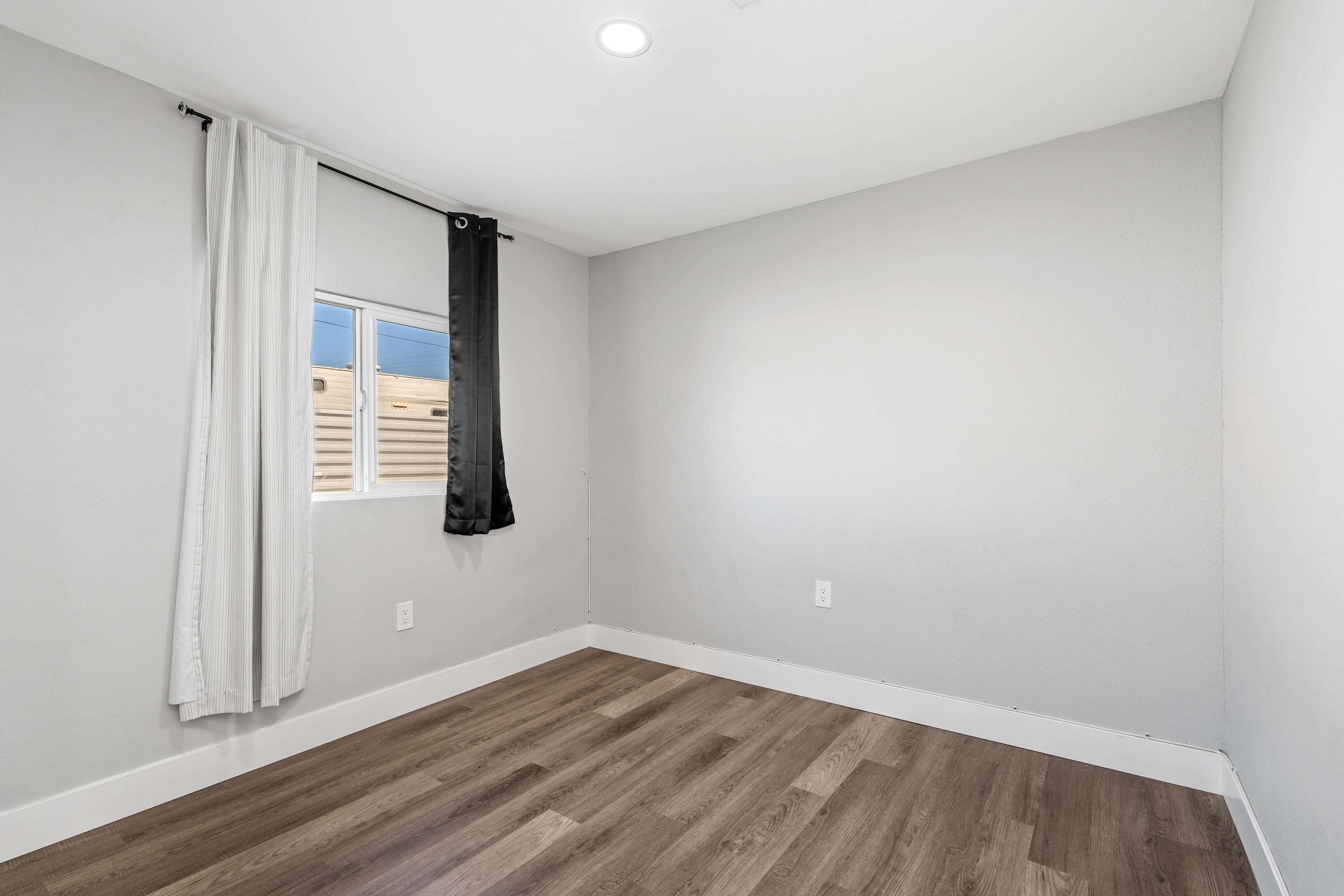 71362 Aurora Road Desert Hot Springs, CA 92241 - Photo 22 of 38 a view of an empty room with wooden floor and a window