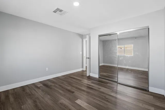an empty room with wooden floor and window