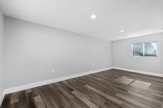a view of an empty room with wooden floor and a window