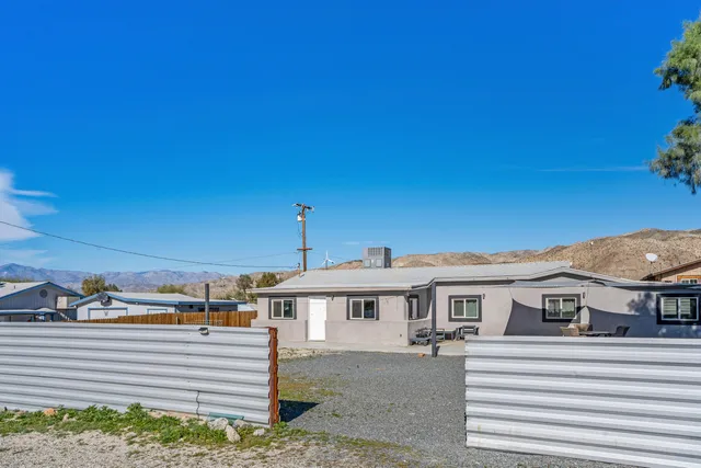 a view of a white house with a big yard and potted plants