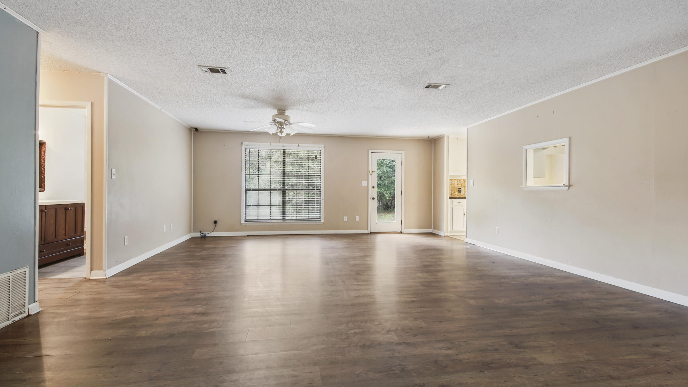 5792 Wildwood Road Crestview, FL 32536 - Photo 8 of 43 an empty room with wooden floor and windows with curtains