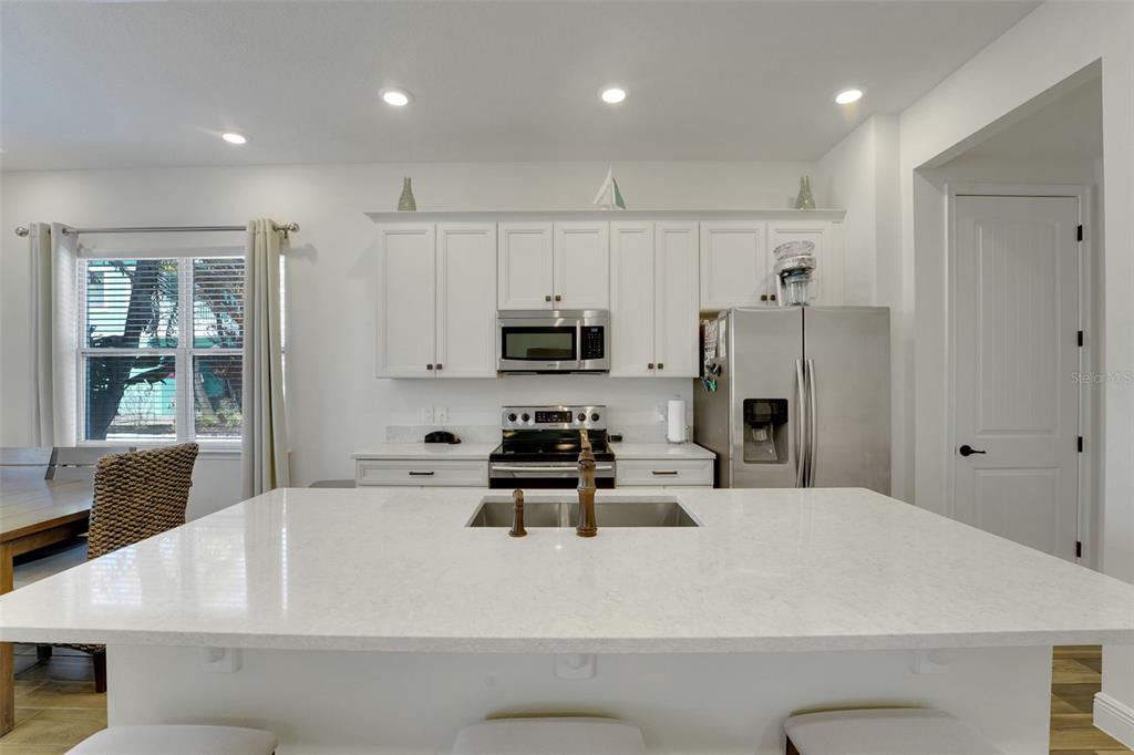 2968 Salted Rim Road Kissimmee, FL 34747 - Photo 8 of 86 a white kitchen with stainless steel appliances kitchen island granite countertop a refrigerator and a stove top oven with white cabinets