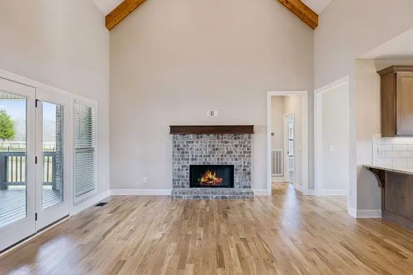 an empty room with wooden floor fireplace and windows