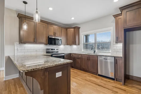 a kitchen with granite countertop a sink stove and refrigerator