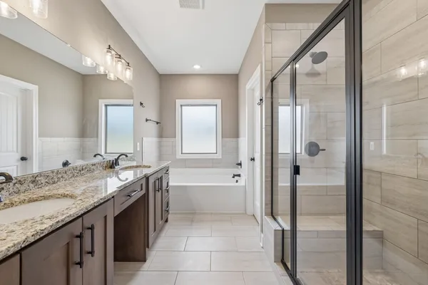 a spacious bathroom with a granite countertop sink a mirror and a bathtub
