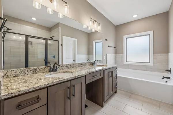 a bathroom with a granite countertop bathtub sink double and mirror