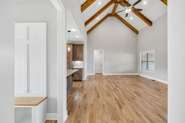 a view of empty room with wooden floor and a window