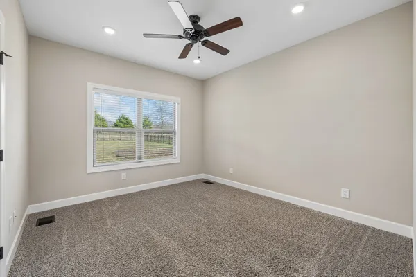 an empty room with a window and a fan