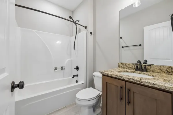 a bathroom with a granite countertop sink a toilet and shower
