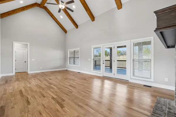 a view of an empty room with wooden floor and windows