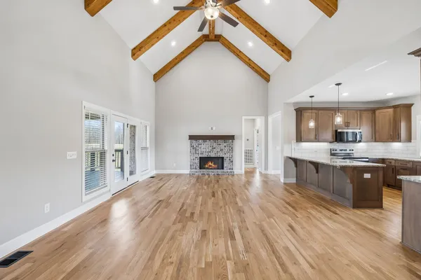 a large white kitchen with a sink and dishwasher a fireplace with wooden floor