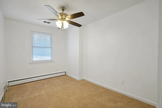 an empty room with a window and a fan