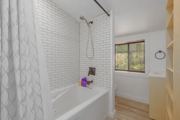 a bathroom with a bathtub a window and shower