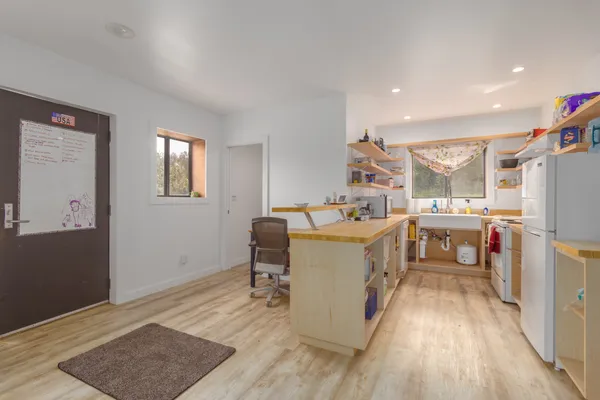 a kitchen that has a lot of cabinets a sink and wooden floor