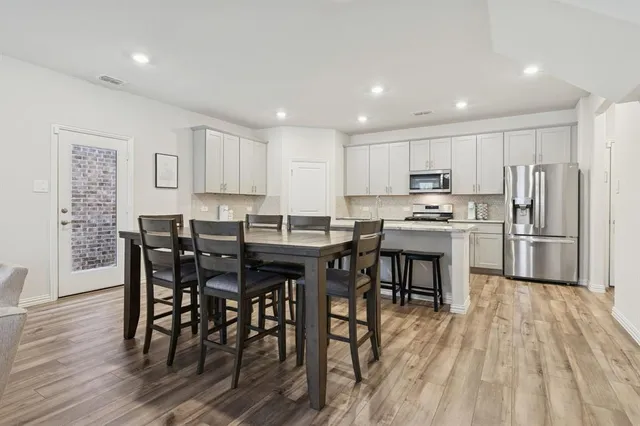 a kitchen with stainless steel appliances a dining table chairs stove refrigerator and cabinets