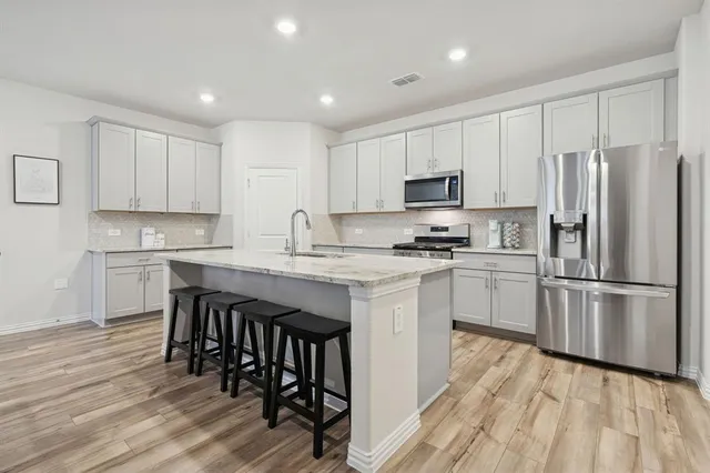 a kitchen with a refrigerator a white stove top oven and white cabinets