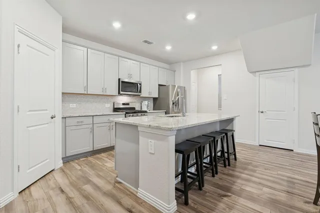 a kitchen with granite countertop white cabinets and stainless steel appliances