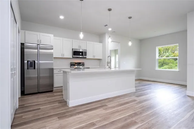 a view of kitchen with kitchen island stainless steel appliances cabinets a sink and a counter top space