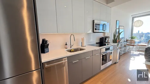 a kitchen with stainless steel appliances a refrigerator a sink a stove and white cabinets