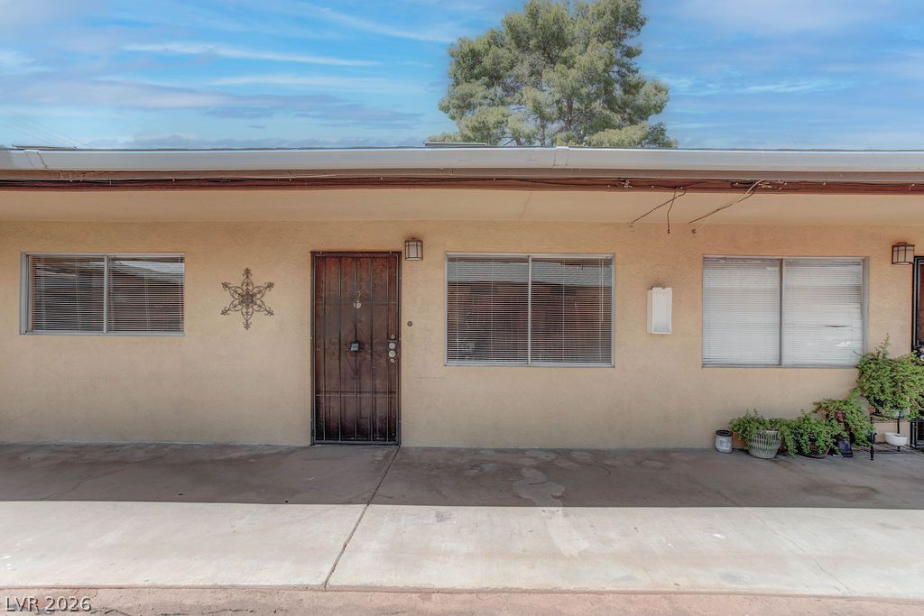 421 North Decatur Boulevard, Unit 2 Las Vegas, NV 89107 - Photo 1 of 21 A modest stucco exterior with multiple windows, featuring a secured entry door.