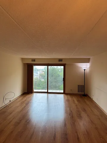 a view of an empty room with wooden floor and a window