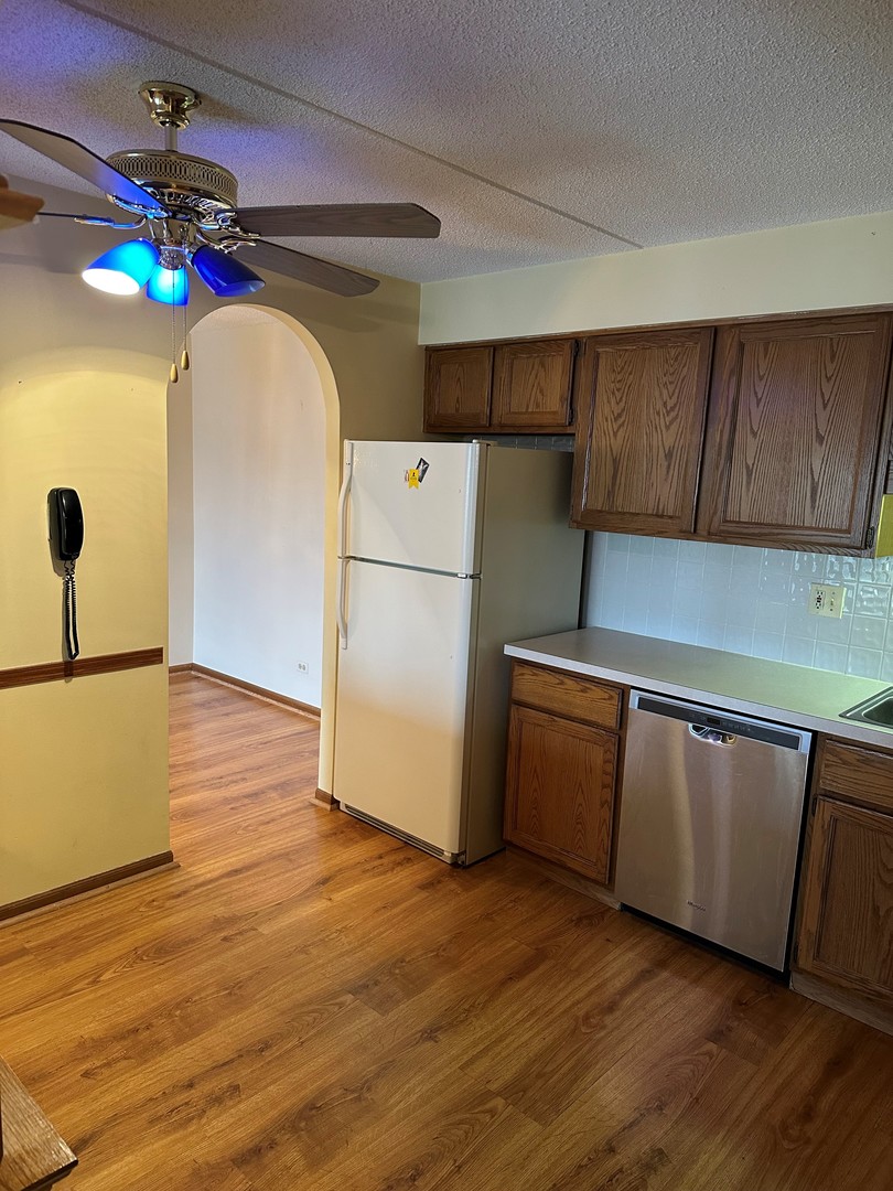 6460 West Belle Plaine Avenue, Unit 407 Chicago, IL 60634 - Photo 5 of 15 a kitchen with a refrigerator a stove top oven a sink and wooden floor