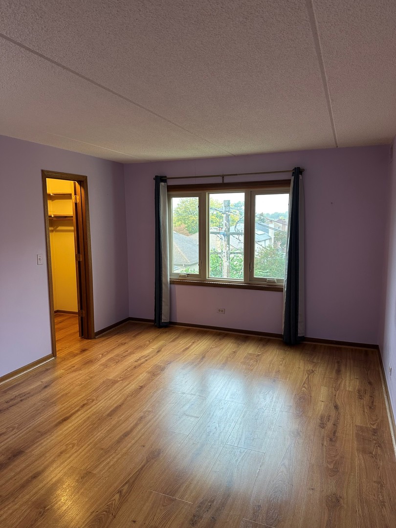 6460 West Belle Plaine Avenue, Unit 407 Chicago, IL 60634 - Photo 6 of 15 an empty room with wooden floor and windows
