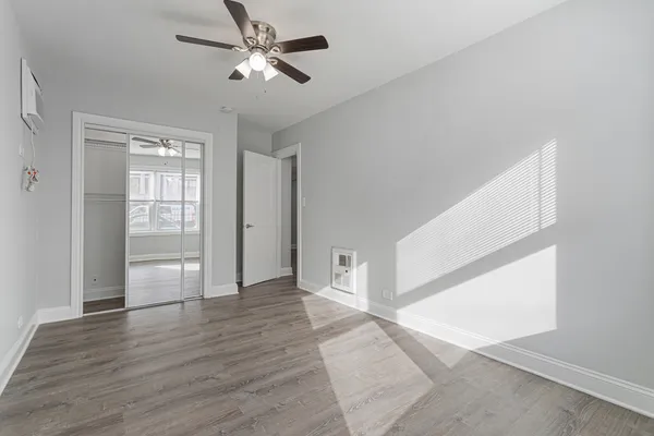 a view of empty room with wooden floor and fan