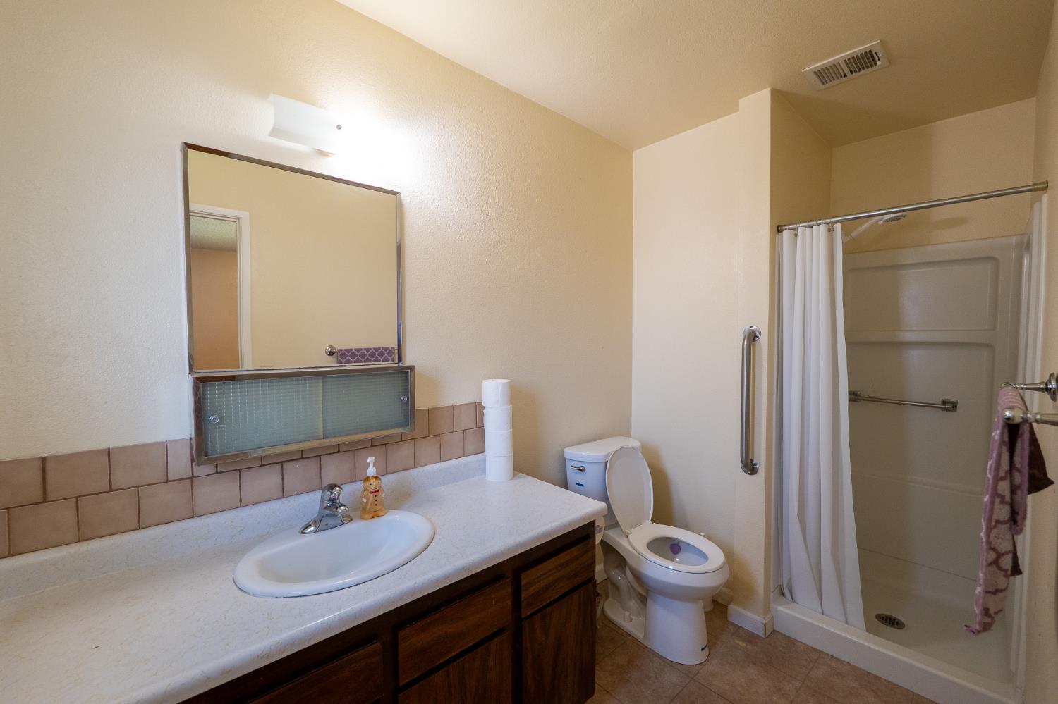 859 11th Street Sanger, CA 93657 - Photo 12 of 28 a bathroom with a toilet a sink a mirror and shower