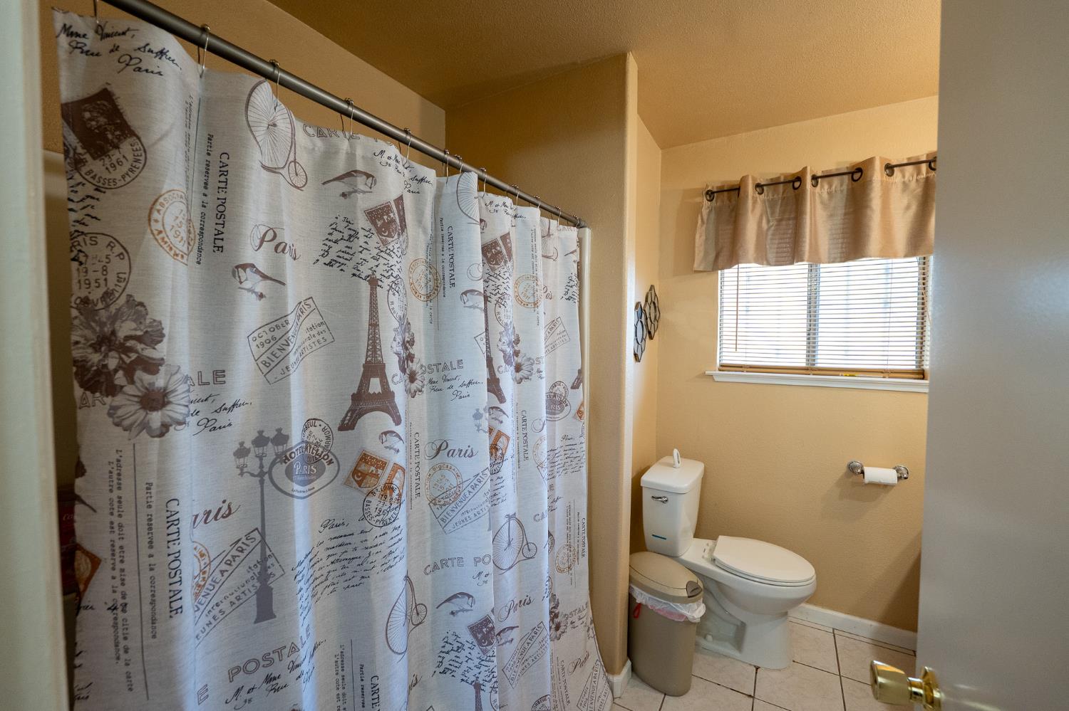859 11th Street Sanger, CA 93657 - Photo 13 of 28 a bathroom with a toilet and shower curtain