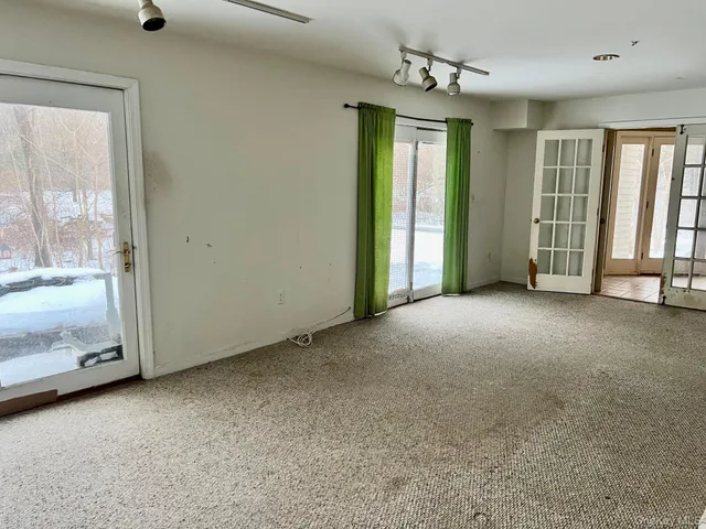 an empty room with chandelier fan and windows