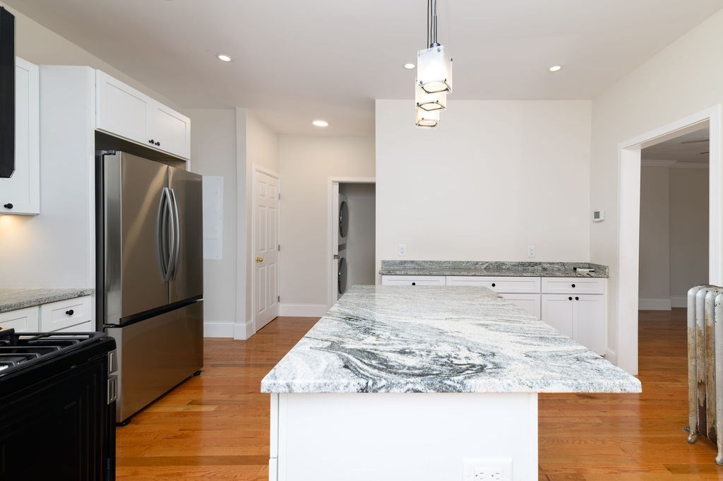 382-384 Adams Street, Unit 3841 Boston, MA 02122 - Photo 6 of 16 a kitchen with kitchen island granite countertop a refrigerator and a stove