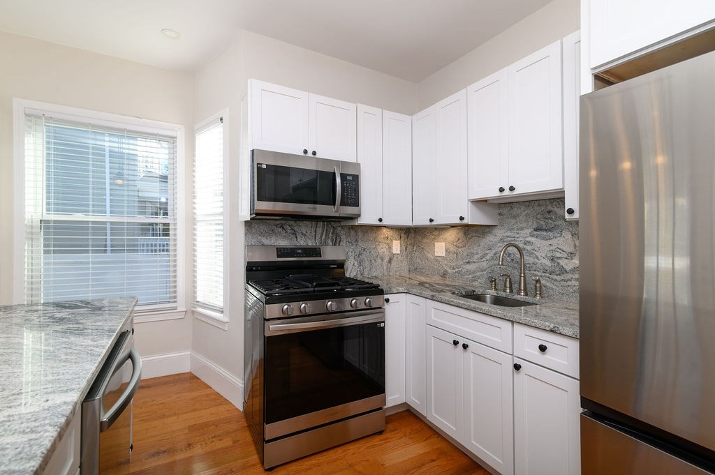 382-384 Adams Street, Unit 3841 Boston, MA 02122 - Photo 7 of 16 a kitchen with stainless steel appliances granite countertop a stove a sink and a microwave