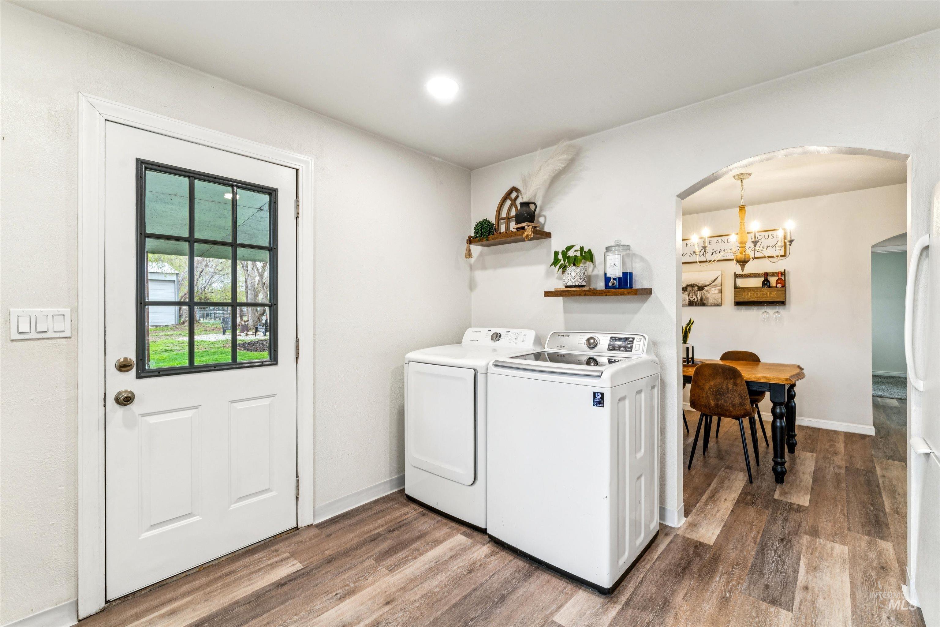 948 South Mill Road Emmett, ID 83617 - Photo 13 of 38 Laundry room with light wood-type flooring, arched walkways, washing machine and dryer, and a chandelier