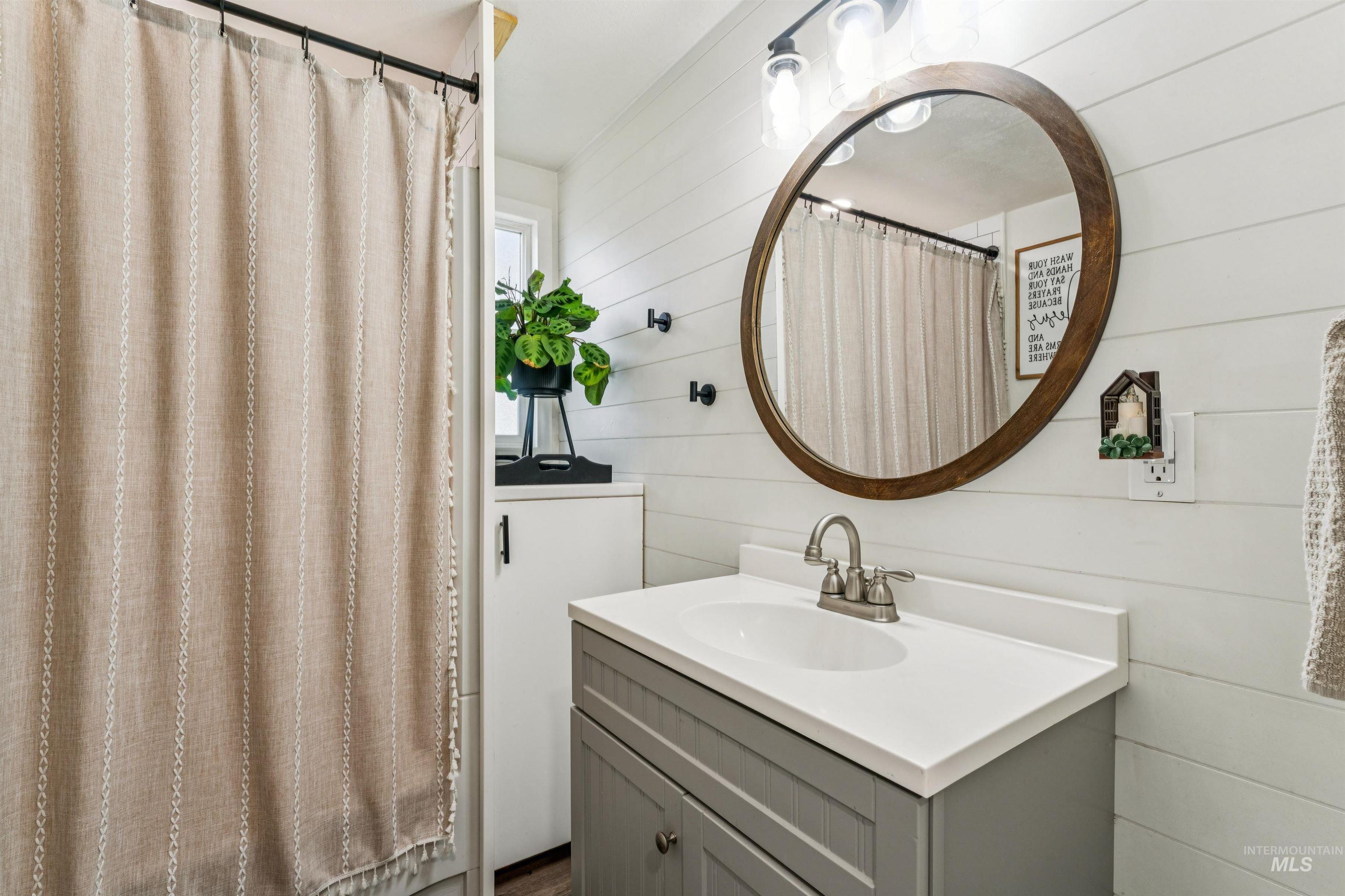 948 South Mill Road Emmett, ID 83617 - Photo 17 of 38 Full bathroom featuring wood walls, vanity, and curtained shower