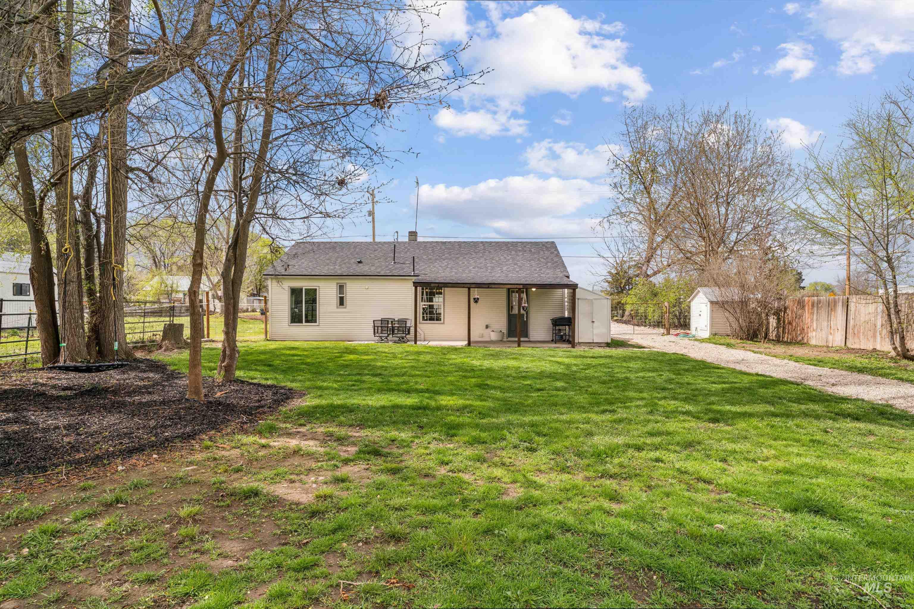 948 South Mill Road Emmett, ID 83617 - Photo 26 of 38 Back of property with a storage unit, a patio, a fenced backyard, and roof with shingles