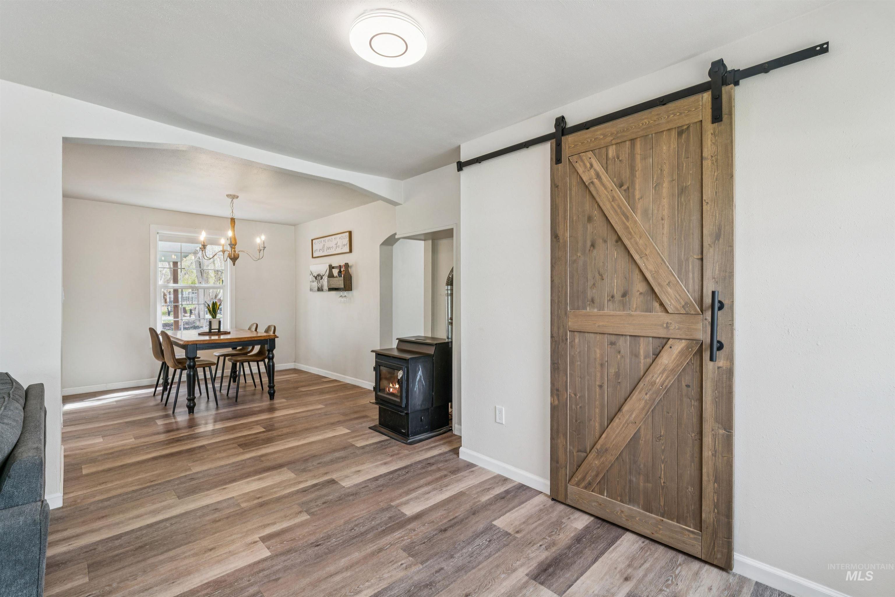 948 South Mill Road Emmett, ID 83617 - Photo 7 of 38 Dining room with a wood stove, wood finished floors, a barn door, and hanging lights