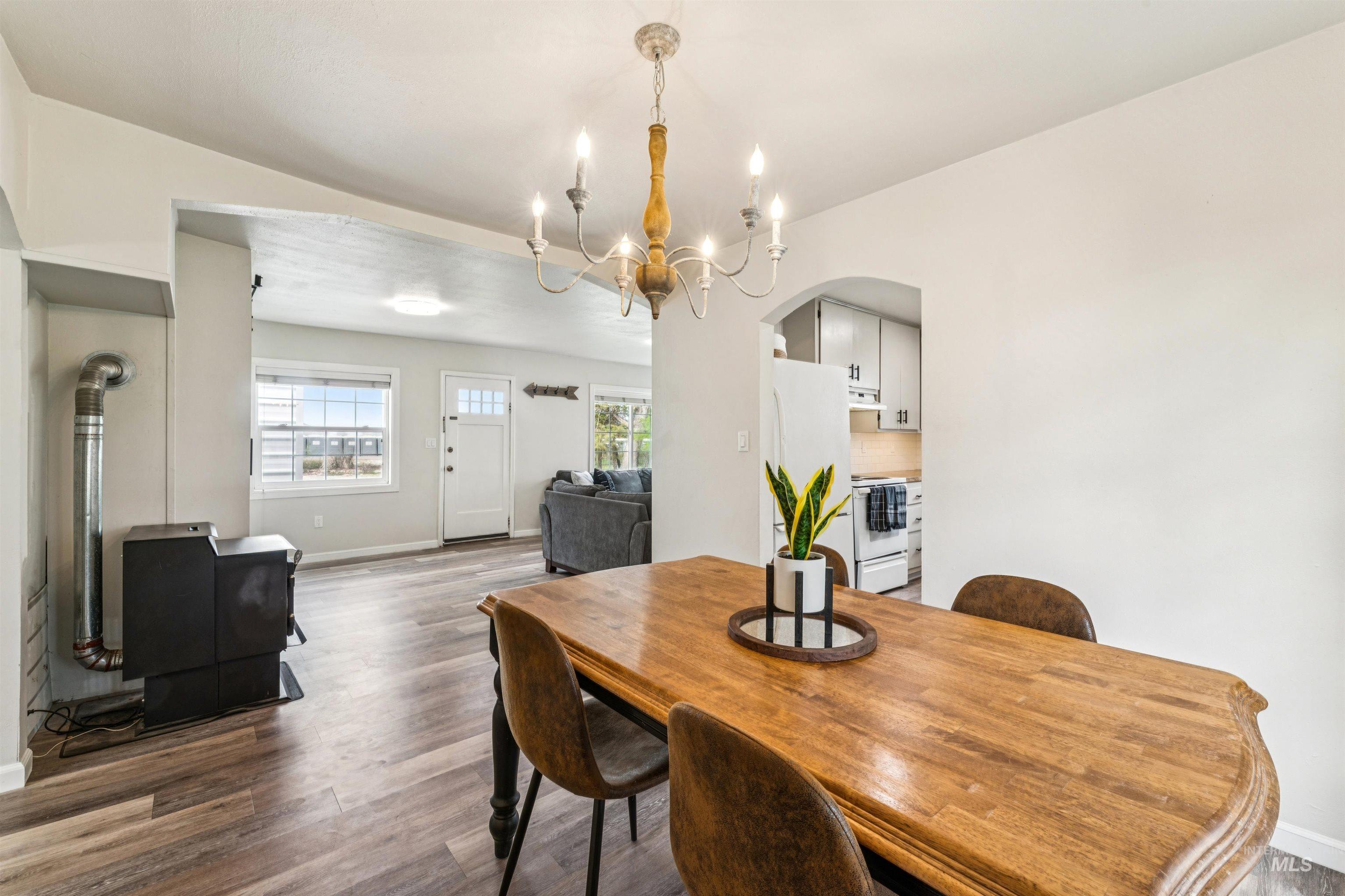 948 South Mill Road Emmett, ID 83617 - Photo 9 of 38 Dining area featuring arched walkways, suspended lighting, wood finished floors, and a wood stove
