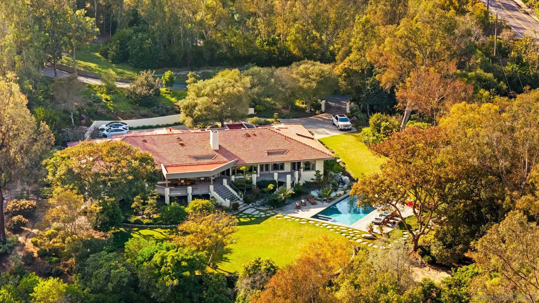 5491 Calzada Del Bosque Rancho Santa Fe, CA 92067 - Photo 1 of 69 a view of a patio with table and chairs under an umbrella with large trees