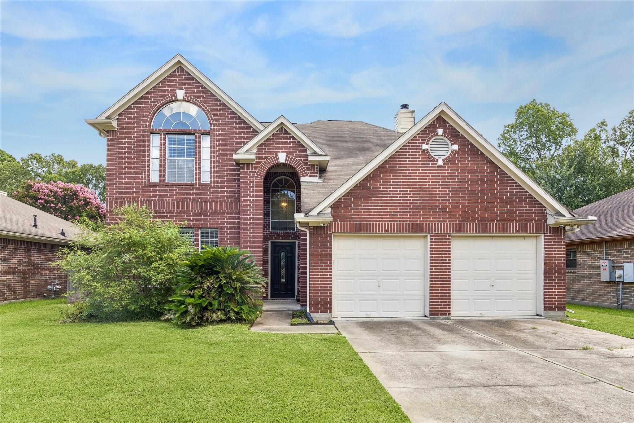 23234 Grand Rapids Lane Spring, TX 77373 - Photo 1 of 30 Stunning two-story brick home with soaring arched window, manicured lawn, and inviting curb appeal on a quiet tree-lined street.