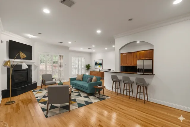 a view of empty room with wooden floor and kitchen