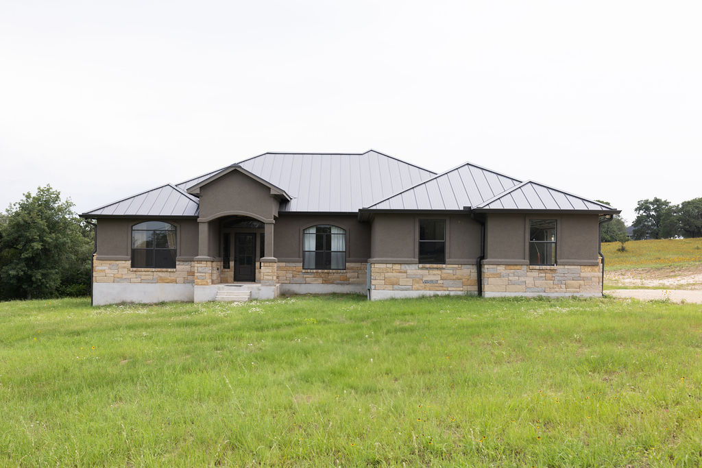 A striking contemporary facade with metal roofing and stone accents on a verdant lot.