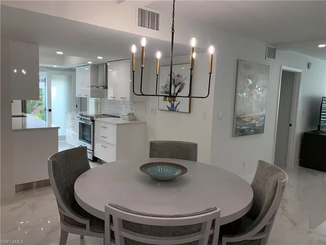 a kitchen with stainless steel appliances granite countertop a dining table chairs and a refrigerator