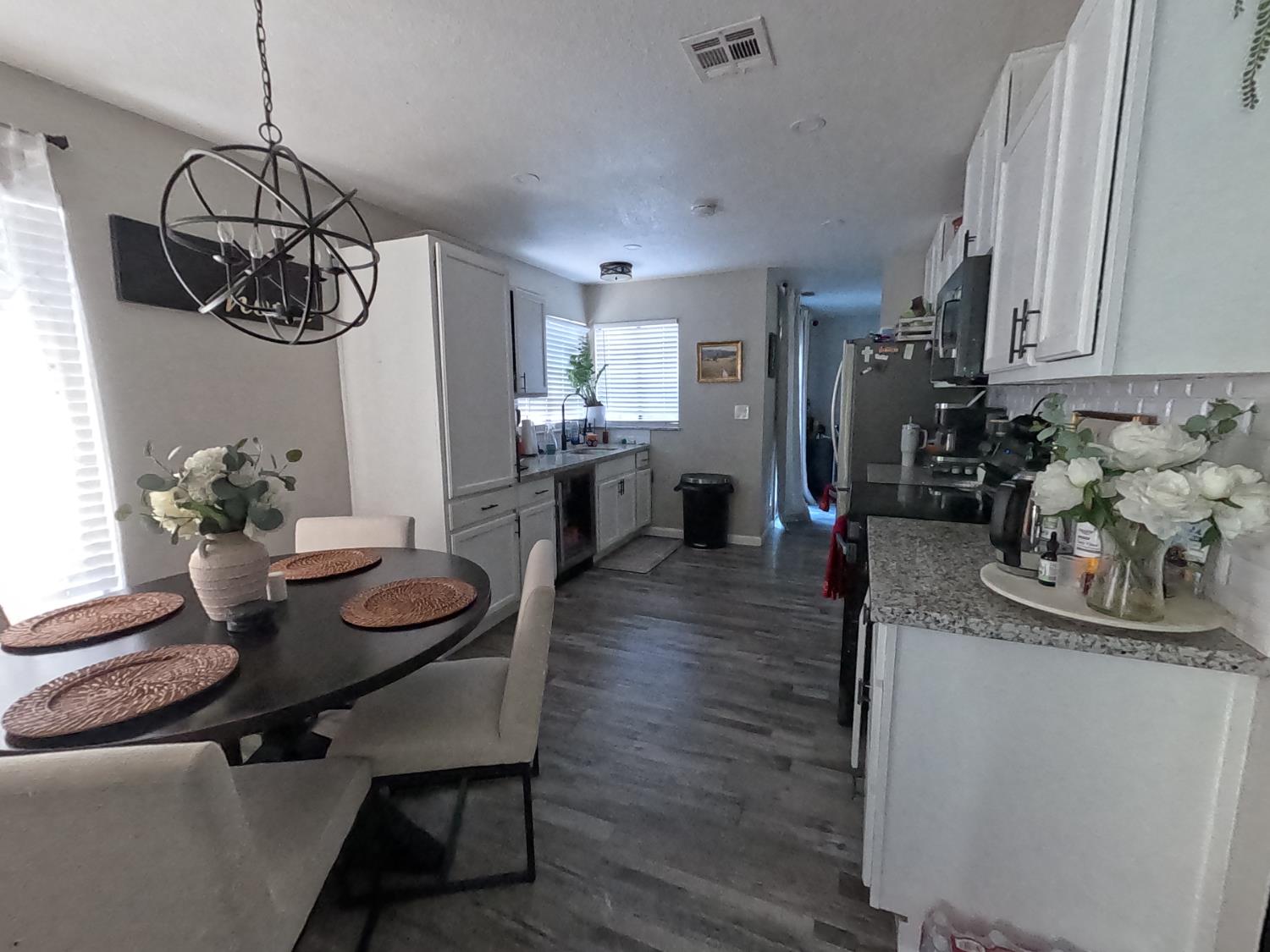 1920 Pontelli Court Stockton, CA 95207 - Photo 8 of 10 a dining room with wooden floor a chandelier a wooden table and chairs