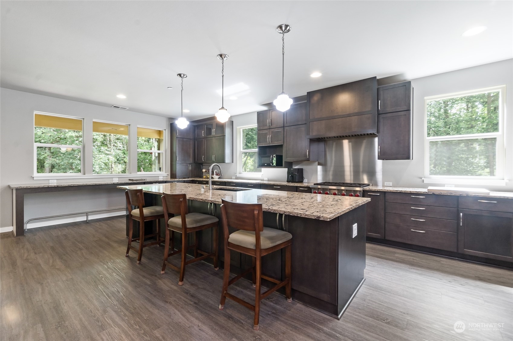 7101 Vandermark Road East Bonney Lake, WA 98391 - Photo 4 of 39 a kitchen with granite countertop a stove a sink a dining table and chairs with wooden floor