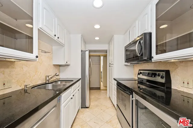 a kitchen with granite countertop a stove a sink and a refrigerator